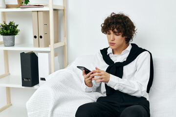 Fototapeta na wymiar curly guy sitting on a white sofa smartphone Lifestyle technology