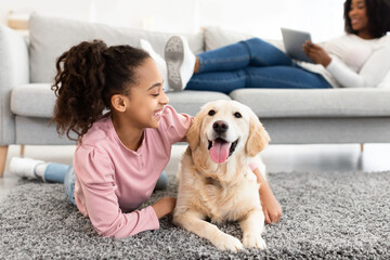Young black teenage girl having fun with dog at home