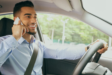 Positive arab guy having phone conversation while driving car