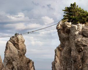Suspension bridge between the rocks. Air mountain road, tourists. Photo.