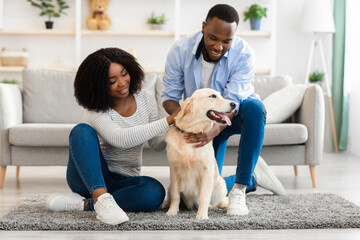 Happy black couple spending time at home with labrador