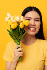 Portrait Asian beautiful young woman bouquet of flowers in hands spring fun posing yellow background unaltered