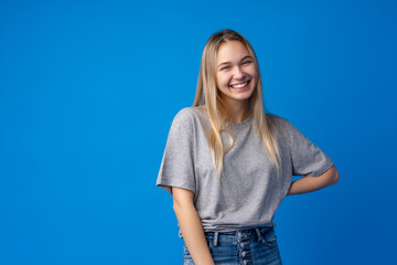 Happy smiling pretty teenage girl laughing over blue background
