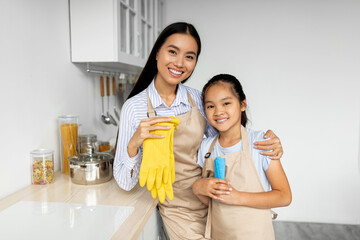Pretty asian girl helping mother with household, standing in kitchen and smiling, enjoying learning housekeeping - Powered by Adobe