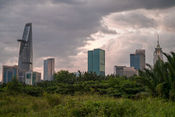 Obraz premium Picture of skyscrapers at sunset in the park with green grass and trees. View in metropolis with modern buildings. High quality photo