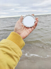 person holding a mirror at beach
