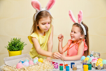 Children in bunnies ears paint Easter eggs and pait each othes. Preparing for Easter. Easter concept