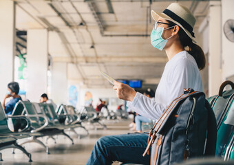 Fototapeta na wymiar Asian woman wearing mask while waiting in bus station for travel during the COVID-19 Pandemic. During your trip should wear a mask to keep your nose and mouth covered when in public.