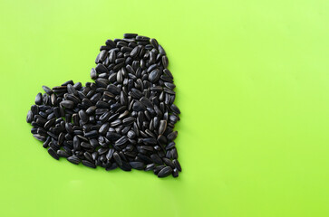 Heart made from sunflower seeds on a green background. Delicious healthy sunflower seeds.