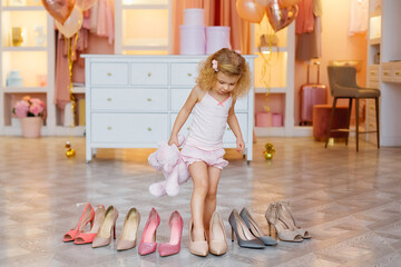 A little girl in pajamas, we put on high-heeled shoes for an adult mom. The child is measuring his...