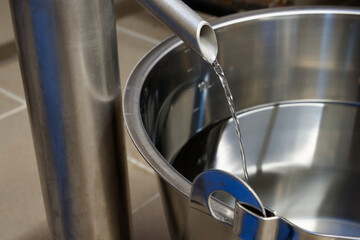 Making gin, Freshly distilled gin runs into a stainless steel bucket after the cooling process.