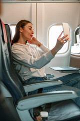 Young woman making selfie in passenger airplane