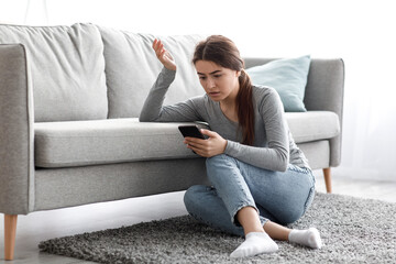 Upset pensive stressed caucasian millennial woman read message, pondering of problem at home