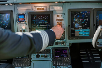 Airline pilot using control panel in aircraft cockpit