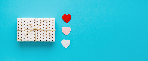 Valentine's day composition with gift box and hearts on blue background. Wedding, birthday, woman's and mother day concept. Flat lay, top view, copy space, place for text, empty, mock up, banner