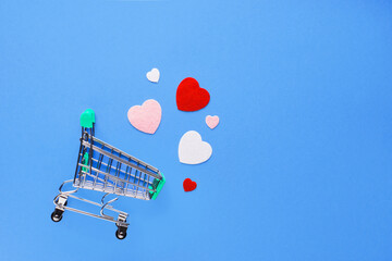 Valentine's day composition with shopping cart and hearts on blue background. Wedding, birthday,...