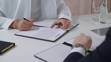 Arab man sign financial documents with a partner businessman, while sitting in the office, handshake between two buisnessman, conclusion of the transaction.
