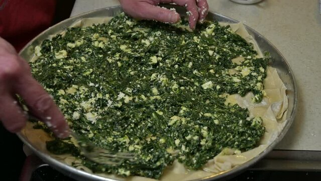 woman is spreading spinach on phyllo dough