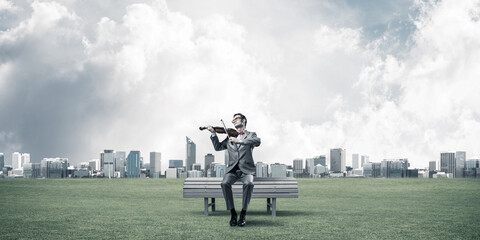 Handsome businessman in park on wooden bench play his melody