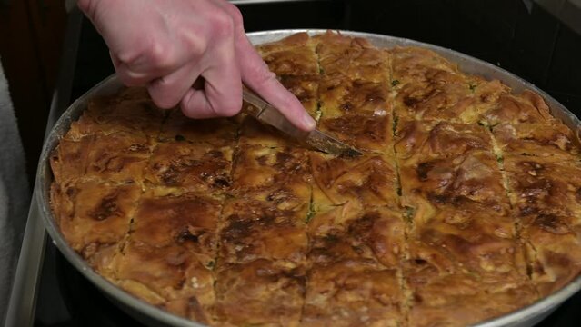 woman is cutting freshly baked spinach pie