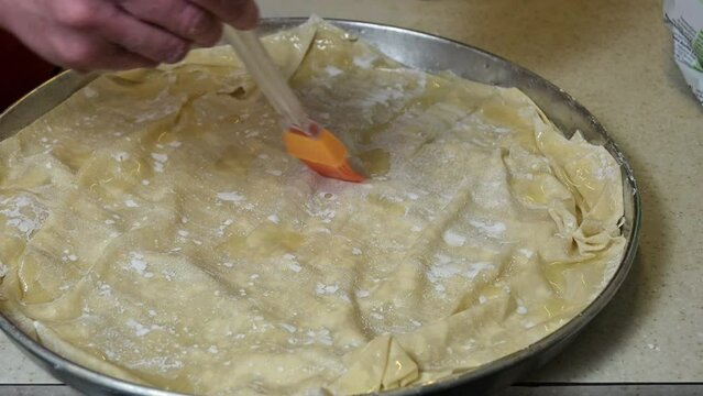 woman is brushing olive oil on phyllo dough, spinach pie preparation