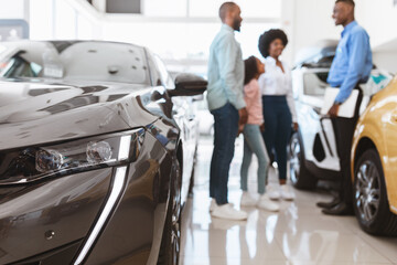 Fototapeta premium Young black family with child buying new car, consulting salesman at auto dealership, selective focus