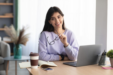 Portrait of smiling young woman sitting at desk