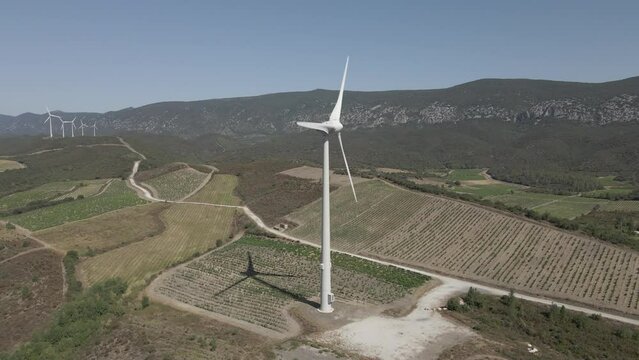 Windmills spin in aerial view of valley vineyards in French Pyrenees