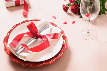 Valentines day table setting with red decoration, gift and roses on pink background. View from above. Valentine's invitation or greeting card. Close up. Special time together.