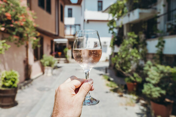 Glass of wine in hand. A glass of young fresh rose wine against the backdrop of a summer cafe in a...