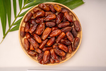 Dried date palm fruit on a wooden plate, date palm fruit with leaf on wooden background
