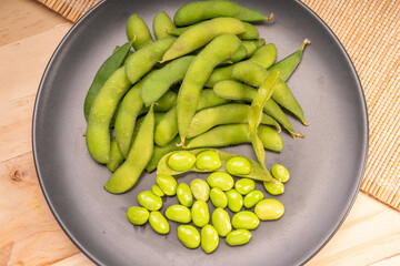Edamame,boiled green soybeans or Edamame bean served in a black  plate on wooden background