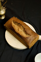 bread on a wooden plate on a black background