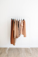 Beige capsule of clothes on a rack over white background