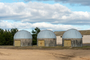 silver silos on agro manufacturing plant for processing drying cleaning and storage of agricultural products, flour, cereals and grain. an old warehouse on a farm with a round roof