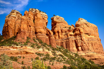 Fototapeta premium Large orange red rock formations and vistas of desert plants leading to mountains and valleys in Sedona, Arizona adds to the beauty of the wilderness