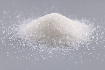 Pile of sugar crystals on grey surface, focus on heap of sweet powder to add in dishes