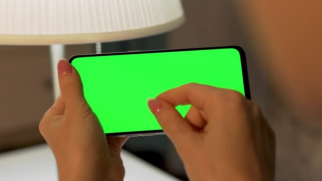Female Fingers Zoom Out Reduction Image Green Screen of Horizontally Phone, Green Background, Chroma Key, Blank, Mockup, Closeup. Woman Uses Smartphone, Internet, Video, Social Networks. 