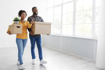 Fototapeta na wymiar Cheerful millennial african american couple enjoying moving in new apartment, excited family in moving day