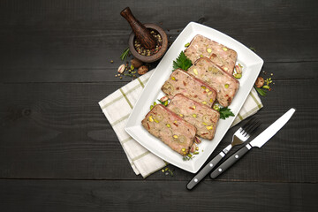 Sliced Traditional French terrine covered with bacon on dark wooden background