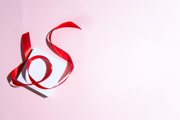 Fototapeta premium White podium and red ribbon on pink background for abstract still life gift giving concept. Copy space