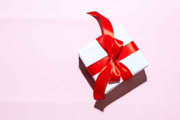 White gift box with red ribbon on pink gradient background for Giving surprise present, mocke up or sale  concept.Copy space