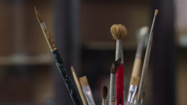 inside artistic workshop of painter, stand with brushes on working table