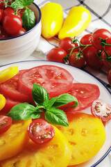 Composition of ripe fresh tomatoes of different varieties, mini bell peppers, spices, rammarine, thyme, basil, chilli pepper, on a wooden background with space for text.