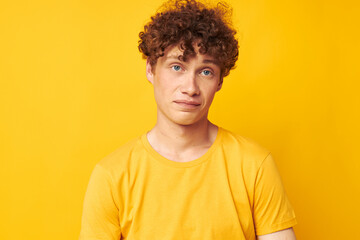 portrait of a young curly man Youth style glasses studio casual wear yellow background unaltered