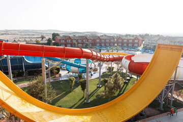 Nice water park with slides and pipes near bungalow houses and hotels. Summer funny landscape of the park at sunset