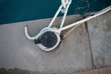 yacht is tied with a white rope to a metal bollard in the port, top view. Safety and support...