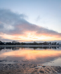 Sunrise on the Mission Bay in California shows boats with their reflections in the orange of the rising sun. Sailors ready to take their sailboats on an adventure