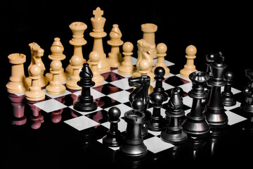 Close up of Chess pieces on a reflective mirror board surface with black background