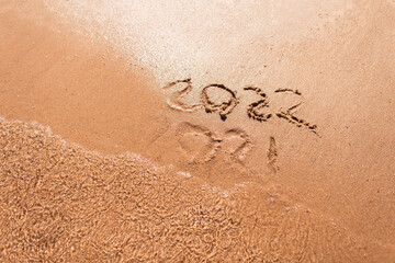 Happy New Year 2022 text on the sea beach. Abstract background photo of coming New Year 2022 and leaving year of 2021